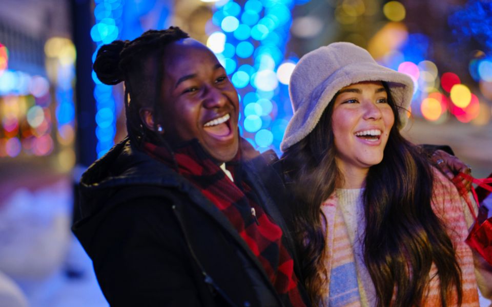 Two young woman, smiling and laughing together, while holiday shopping