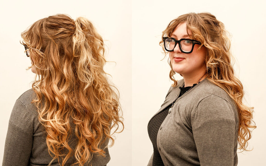 A hairstylist with her wavy hair pulled back in a half-up ponytail