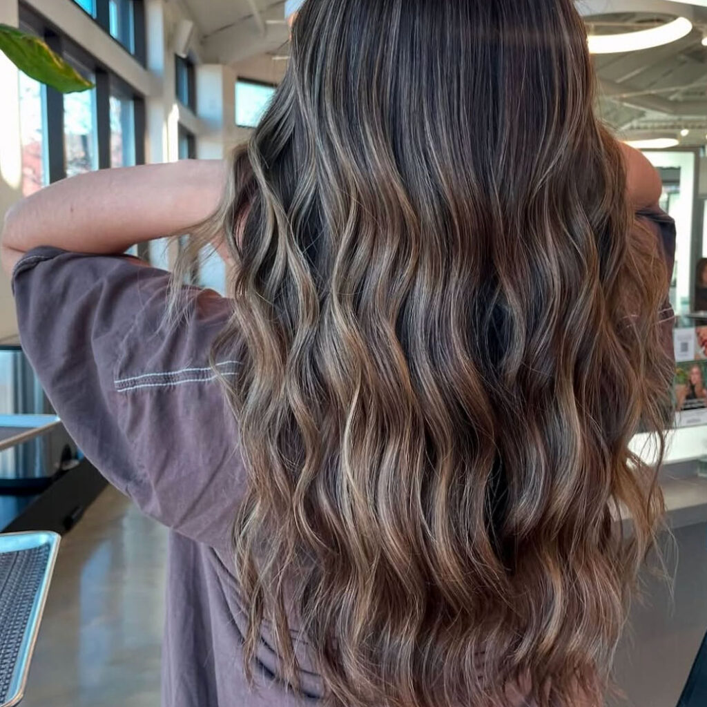 A beautiful brunette dimensional hair color that has added warmth and sun-kissed highlights to the woman's long hair