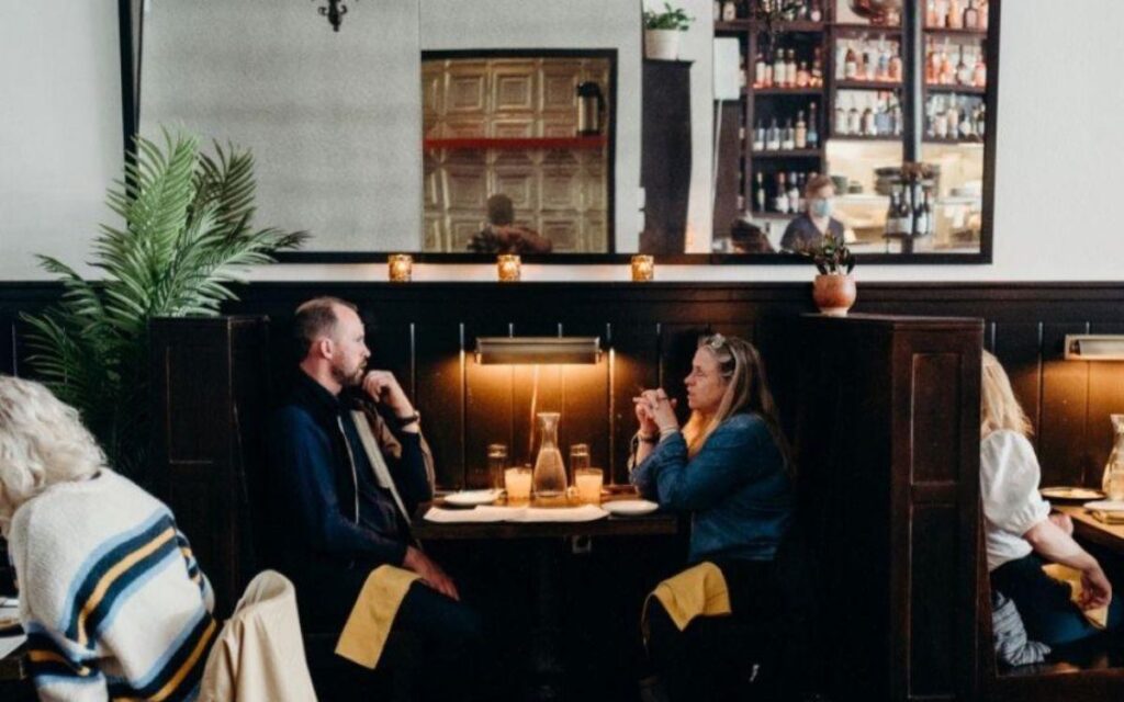 Two people seated in a cozy booth at Petite León in Minneapolis