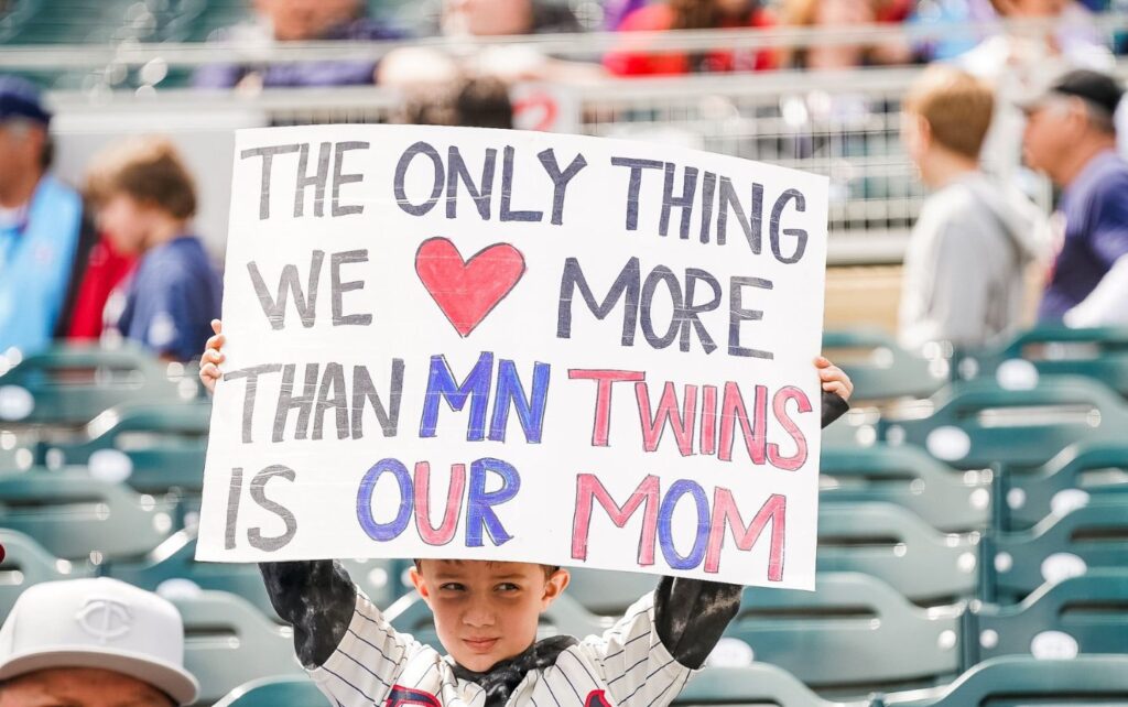 A young Twins fan at Target Field in Minneapolis holding up a sign that reads, "The only thing we love more than MN Twins is our mom."