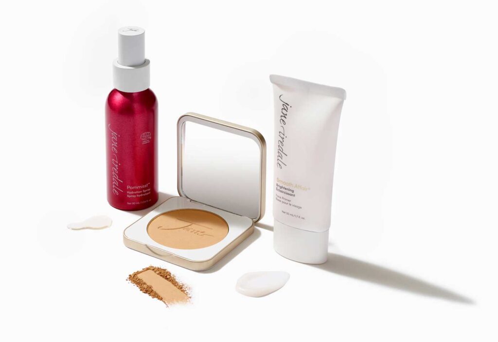 A selection of Jane Iredale clean makeup products on a white countertop, including facial mist, POMMISST.